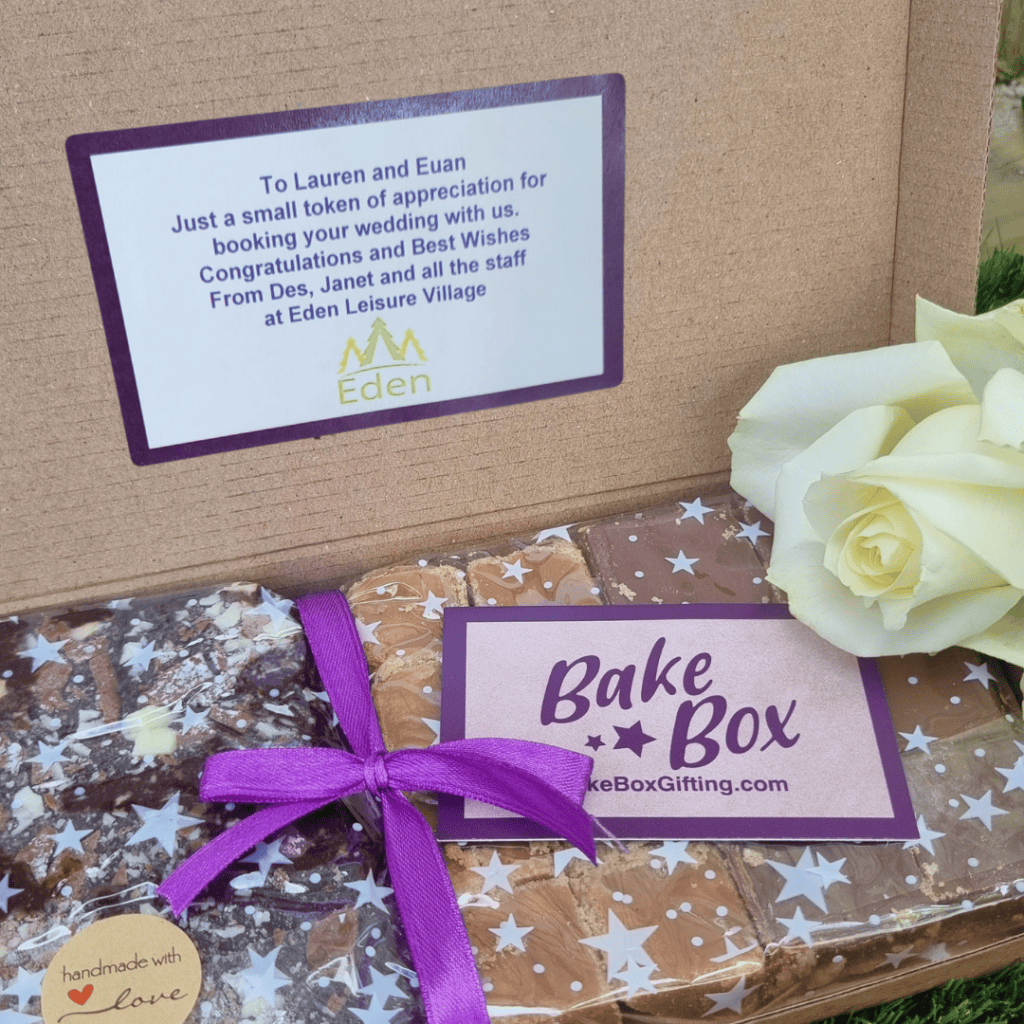 BakeBox Gift showcasing the BakeBox Gifting trio of treats: chocolate brownies, caramel shortcake and scottish tablet. Sticker on inside lid of BakeBox has a message from Eden Leisure Village to Lauren and Euan to thank them for booking their wedding there.